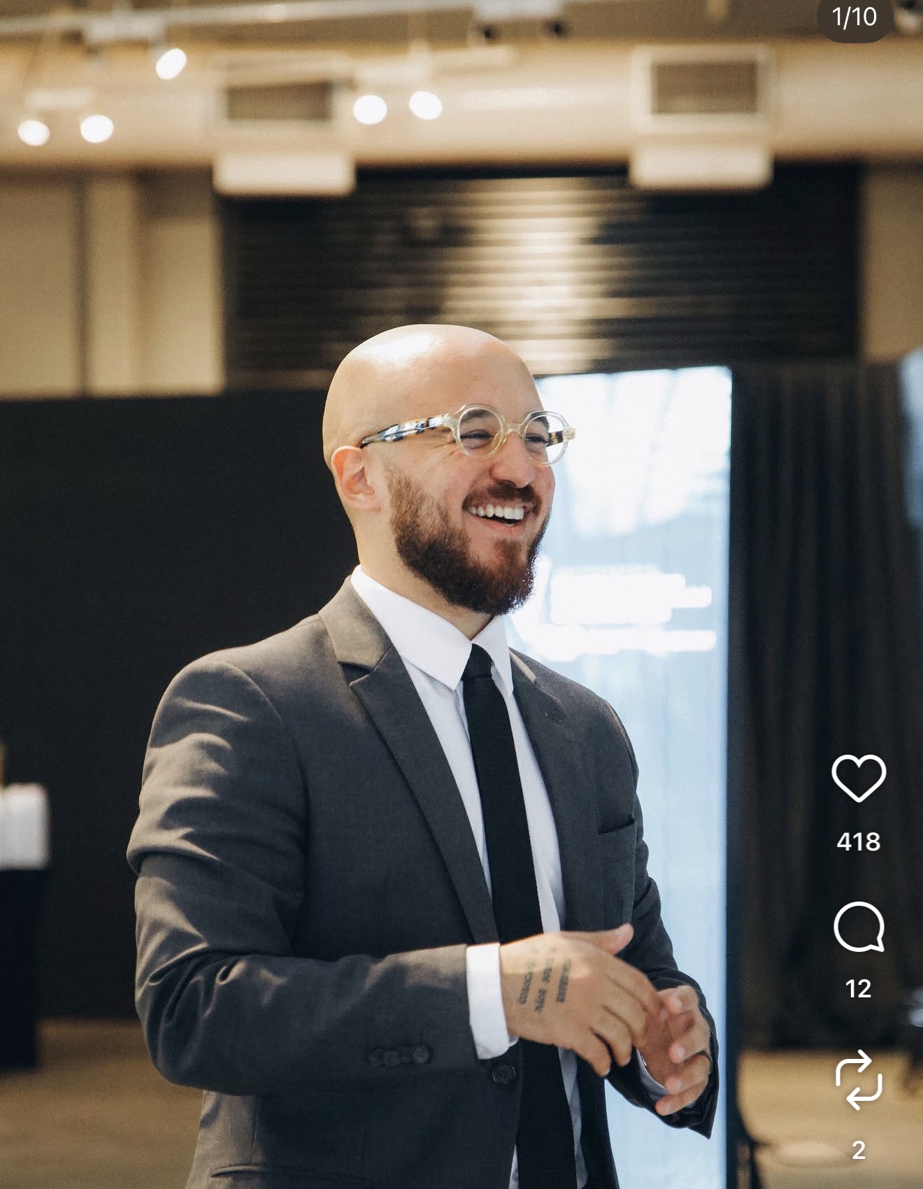 Caio Escovino de terno, sorrindo durante um evento corporativo.